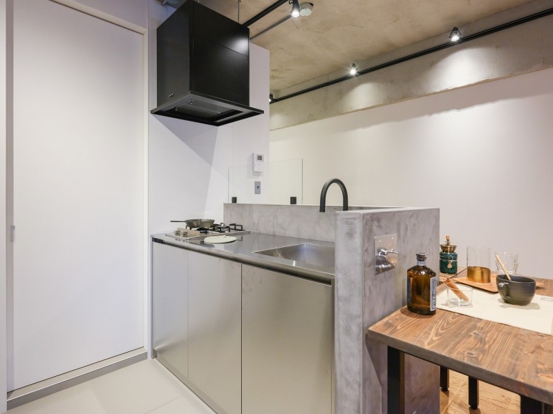 キッチンはお部屋の雰囲気に調和するシルバートップを採用。木の経年変化をも楽しめる収納豊富なカップボードを配置しました。