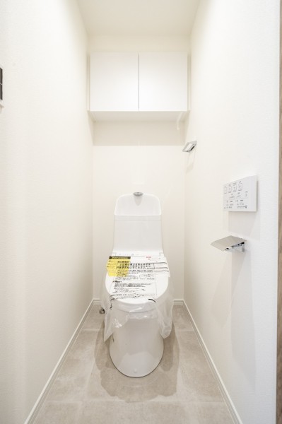 TOTO製ウォシュレット一体型のトイレは、お掃除の手助けをしてくれる便利機能が搭載されています。背面には収納に便利な吊戸棚収納を備え付けました。
