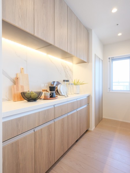 システムキッチンとお揃いのカップボードは間接照明がカウンター部分を照らし、よりいっそう格調高い雰囲気をもたらします。料理や家事の導線を考えて収納することが可能で、実用性もある設備です。