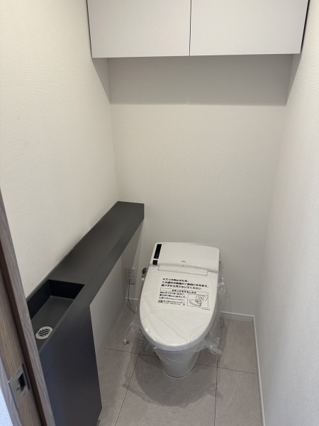 ウォシュレット一体型のトイレは、お掃除の手助けをしてくれる便利機能が搭載されています。上部には収納に便利な吊戸棚を備え付けました。