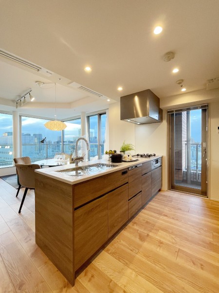 上質なお部屋に溶け込む、木目調デザインの田中工藝製オープンキッチンです。キッチン横手の扉はバルコニーへとつながっているため、採光性や換気面も良好ですね。