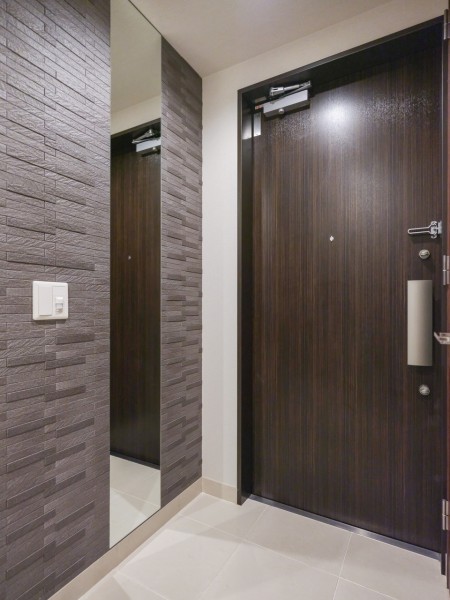 住まいの顔となる玄関は、天井までの背の高いミラーとグレートーンのタイルデザインが格調の高さを感じさせる上質な空間です。