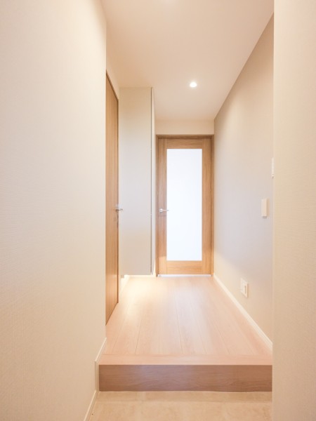 フットライトが足元を優しく照らす玄関ホールです。優しい色合いのアクセントクロスを取り入れ、心安らぐ空間を演出しています。