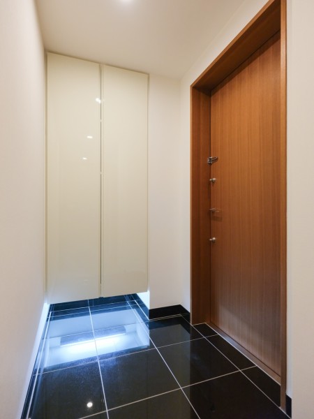 フットライトからのびる光が足元を優しく包み込む玄関です。天井までの高さがあるシューズボックスあり、玄関をすっきり綺麗に保てます。