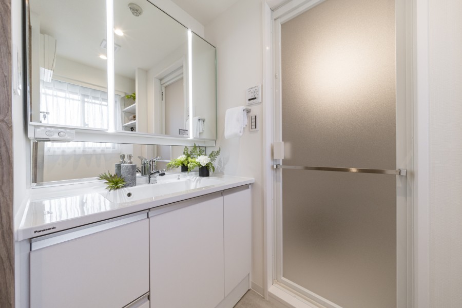 白を基調とした清潔感溢れるデザインの洗面化粧台です。三面鏡の裏側や足元のキャビネットなど、収納豊富で実用的な洗面空間です。