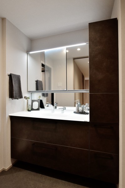 大きな三面鏡に明るく照らすライトで身だしなみを整えやすい洗面台です。サイドキャビネットを設置し、小物類からリネン類までたっぷりと収納できます。