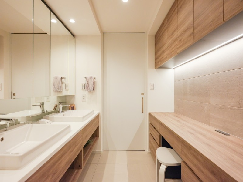 洗面化粧台にはまるでホテルのようなダブルボウルデザインを採用しました。田中工藝製のこだわりの仕様です。背面のリネン庫も収納豊富で、大きな鏡は身だしなみも整えやすく、朝の慌ただしい時間帯も快適です。