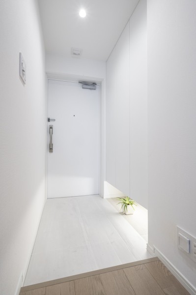 住まいの顔となる玄関は明るいホワイトカラーで仕上げました。フットライトからのびる光が足元を優しく包み込む気品溢れる玄関です。