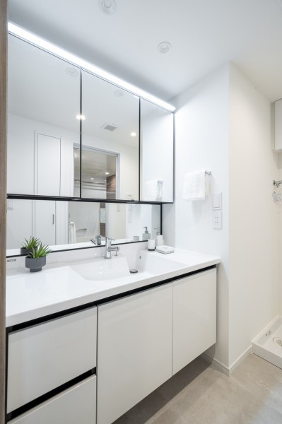 白を基調とした清潔感溢れるデザインの洗面化粧台です。三面鏡の裏側や足元のキャビネットなど、収納豊富で実用的な洗面空間です。