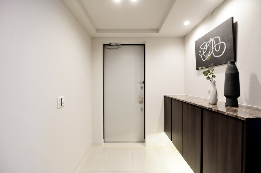 玄関は爽やかなホワイトのタイルとシックなブラウンのシューズボックスがエレガントにゲストや家族を迎えてくれます。ピクチャーレールを設置し、アートでお好みの空間を作れます。