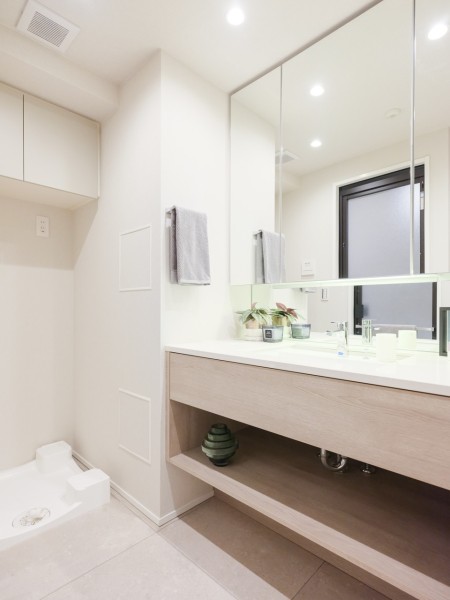 空間に美しく溶け込むスタイリッシュなデザインの洗面化粧台。三面鏡裏や足元の収納など使いやすさも兼ね備えています。洗濯機置場の上には便利な吊戸棚を備え付けています。