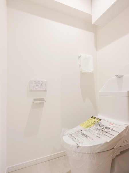 TOTO製ウォシュレット一体型のトイレは、お掃除の手助けをしてくれる便利機能が搭載されています。背面には収納に便利な吊戸棚収納を備え付けました。