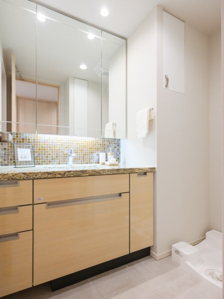 入浴後の豊かな時間を演出し、心からくつろげるプライベートスペースの洗面空間です。大きな三面鏡で身だしなみも整えやすく、収納豊富で実用的な洗面化粧台です。