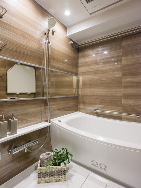 横長ミラーの効果で実際のサイズよりも広がりを感じるバスルームです。光沢のある木目調パネルが高級感を漂わせ、毎日のバスタイムを贅沢に、豊かにしてくれます。