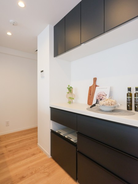 背面にはお揃いの面材が上品さを演出する、収納豊富なカップボードを備え付けました。下段にはダストボックスを格納しやすいスペースを設けています。