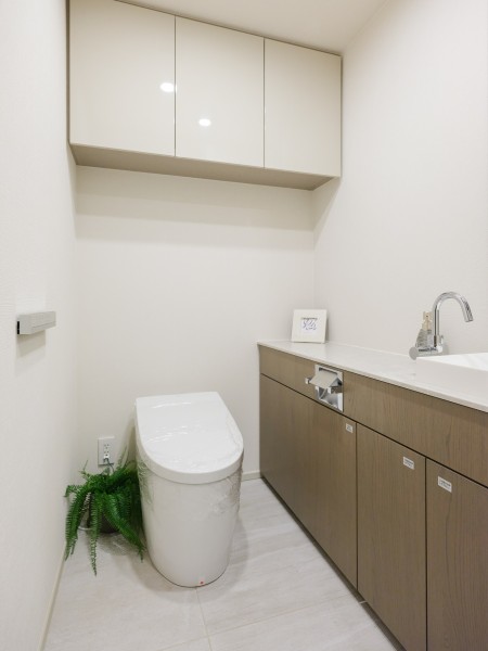 レストルームには、洗練されたお部屋にぴったりなスマートデザインのタンクレストイレと手洗いカウンターが設置されています。上部吊戸棚もあり、空間をすっきり保つことが可能です。