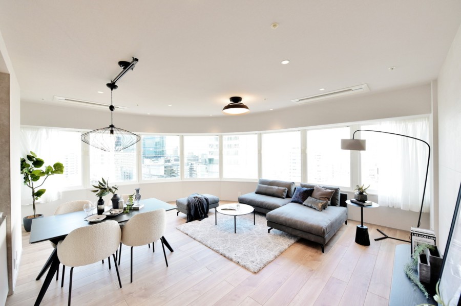 Rを描いた印象的なリビングです。一面窓になっていますので、梅田の景色や夜景をパノラマ眺望で堪能出来ます。床暖房が設置されていますので、冬も足元から暖かくお寛ぎいただけます。