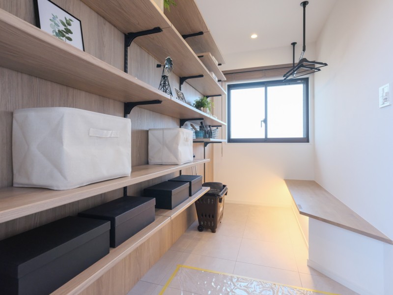 玄関には明るいフリースペースを設けました。アウター類を吊り下げるパイプ下のカウンター部分は、靴の着脱の際には腰掛けとしてもお使いいただけます。