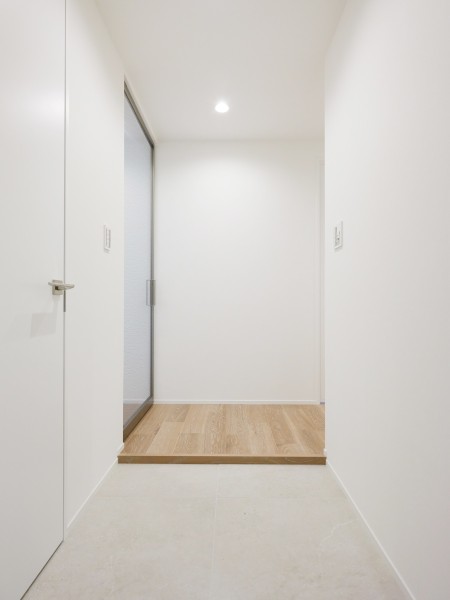 白を基調とした清潔感あふれる玄関です。リビングへのドアには、Raiki製のガラス建具を採用し、上品な印象を演出しています。