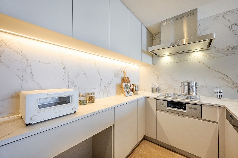 大理石調の壁が格式高い雰囲気となっているコの字型キッチンです。椅子を収納できるスペースがあるため、お料理の合間の休憩をすることができます。収納棚がたくさんあり、収納時に活躍します。