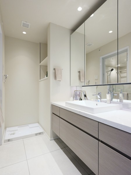 ホワイトカラーで統一された洗面室は、明るく清潔感溢れる空間です。洗面台は三面鏡裏と足元に収納棚があり、収納することで広くお使いいただけます。洗濯機置き場の隣に棚があり、見せる収納ができます。