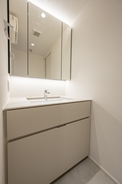 洗面室には、田中工藝製の洗面台を設置いたしました。三面鏡裏と足元に収納棚を造作し、収納性を高め、洗面室を広くお使いいただけます。身支度時間を快適にご利用いただけます。