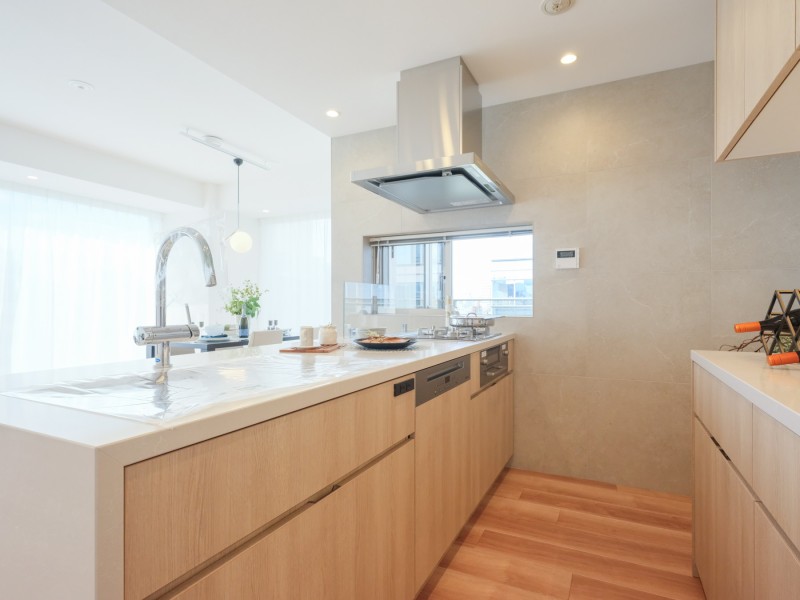 ホワイト×ベージュのシステムキッチンは田中工藝製です。お部屋と調和する色調で、ゆとりがある広さのためご家族やお友達と並んでお料理を楽しむことができます。３口コンロやグリルがあるためお料理の幅が広がります。