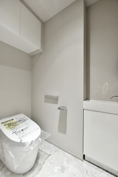 TOTO製のウォシュレット一体型タンクレストイレ新規交換済みです。吊戸棚を設置しましたので、小物類の収納にも便利です。手洗いカウンターを設置していますので、家族やゲストが気兼ねなく使用でき、いつも清潔な空間を保てます。