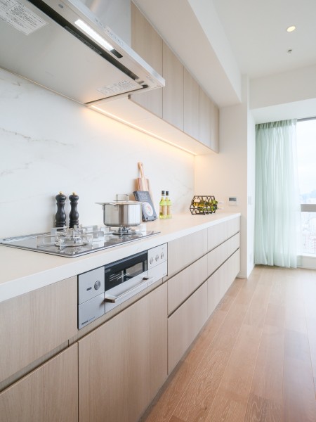 ガスコンロはガラストップ仕様で、表面がなめらかなためお手入れが簡単です。高い耐久性と耐熱性を備え、長く安心してお使いいただけます。吊戸棚や足元に収納があり、使いやすいキッチンを実現しました。