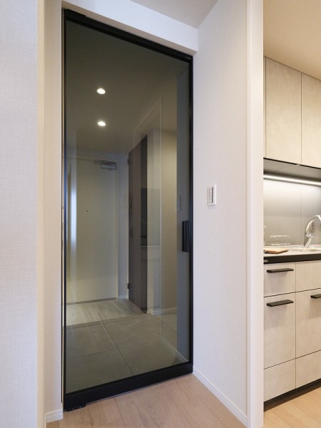 リビングへ続く扉はガラス仕様で、空間に開放感と軽やかさを演出します。周囲の素材と調和する仕上げで、住まい全体に落ち着いた雰囲気を添えています。