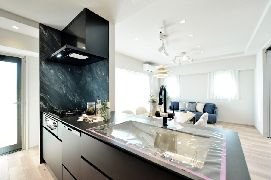 このお部屋のためにデザインされた田中工藝製オリジナルシステムキッチンです。空間を引き締めるブラックと石目調のキッチンパネルが印象的で、インテリアの役割も果たしています。食器洗い機完備です。