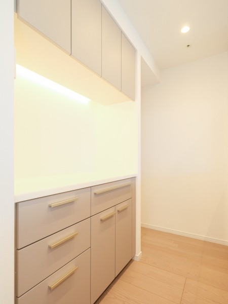 キッチン背面には、デザインを統一した機能的なカップボードを配置しました。食器や調味料がスマートに収まる設計です。棚下灯の光がアクセントとなり、日々使う調理家電やこだわりの雑貨をより魅力的に演出します。