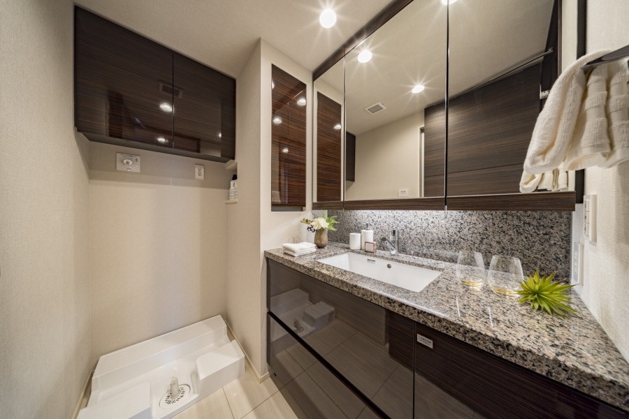 日常を心地よくリセットする、ホテルライクな洗面空間です。こまごまとした物が多くなりがちな洗面室には、埋込棚や洗面化粧台の三面鏡裏、足元のキャビネットなど収納スペースをたっぷり確保しています。