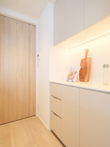 キッチン背面には、デザインを統一したカップボードと吊戸棚を設置しています。収納力に優れ、調理器具や食器類をすっきりと整理できる使い勝手の良い設計です。
