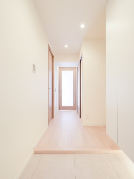 明るい木目の建具とフローリングが調和する廊下です。正面の採光ドアが視線を先まで通し、空間に軽やかな印象を与えています。