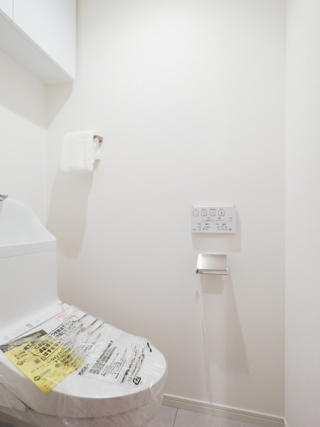 温水洗浄便座付きトイレへ新規交換済みです。白を基調とした清潔感のある空間で、上部には収納棚が設けられ、日用品の整理にも便利です。