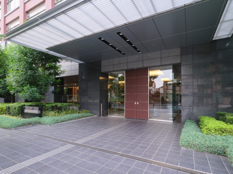 ガラスと石調素材を組み合わせたエントランスです。植栽が整えられたアプローチが住まいの入口に落ち着いた印象を添えています。