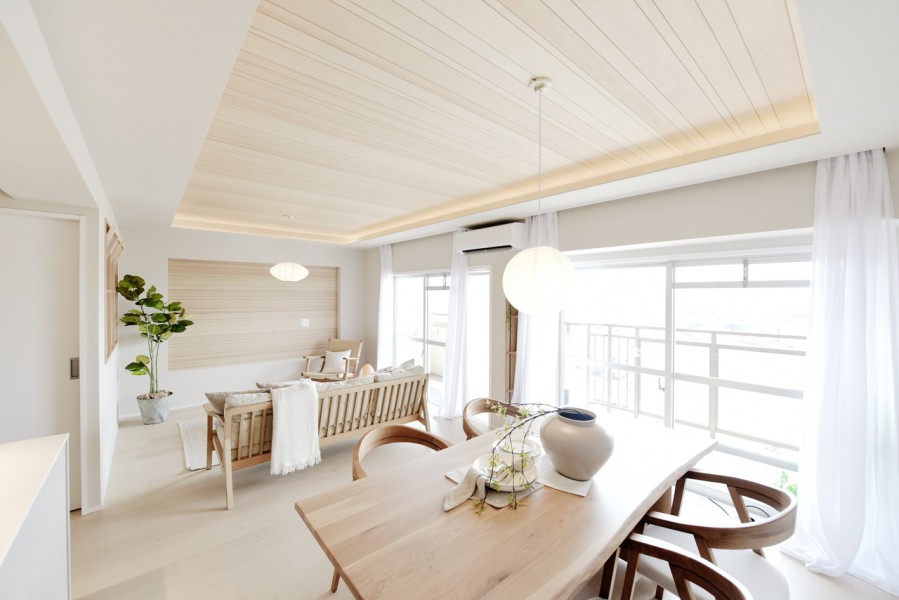 南向きの大きな開口部から明るい陽光が降り注ぐリビングダイニング。無垢突板材をあしらった折り上げ天井と間接照明が上質な空間を演出し、最上階ならではの開放感と眺望を日常の中で楽しめます。