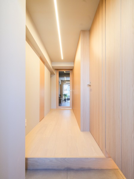 木目調の建具とライン照明が調和する玄関ホールです。シューズボックスが建具に溶け込むノイズレスな空間設計。すっきりとしたスペースで、リビングへと続く奥行きも感じられます。