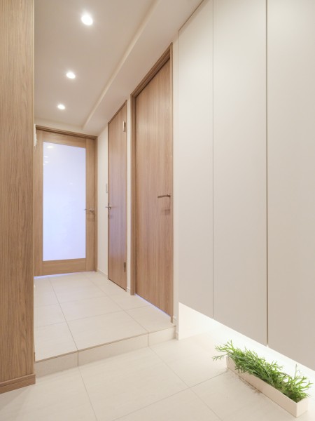 木目調の建具と白を基調とした内装が調和した玄関です。天井までの高さがあるシューズボックスを備え、すっきりとした迎賓空間を演出しています。