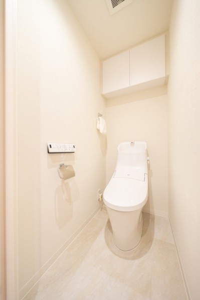 LIXIL製シャワートイレです。ペーパーホルダーとタオルリングはステンレスで統一されていてシンプルな空間。トイレットペーパーの収納に便利な吊戸棚備え付けです。