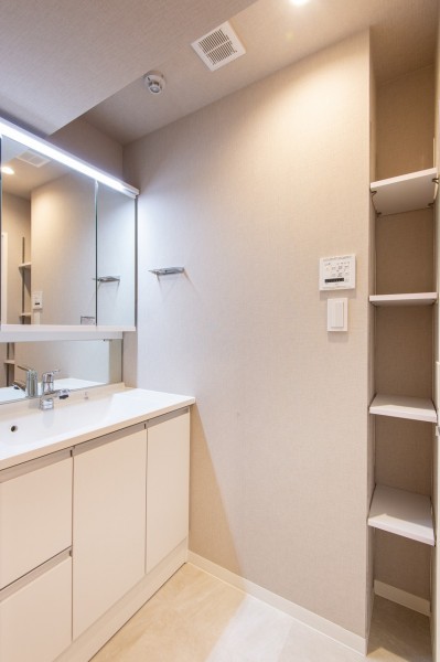洗面室は三面鏡のミラーキャビネットに小物を収納でき、すっきりとした空間を保てますね。浴室扉横の棚もタオルや着替えを置ける便利スペースです。