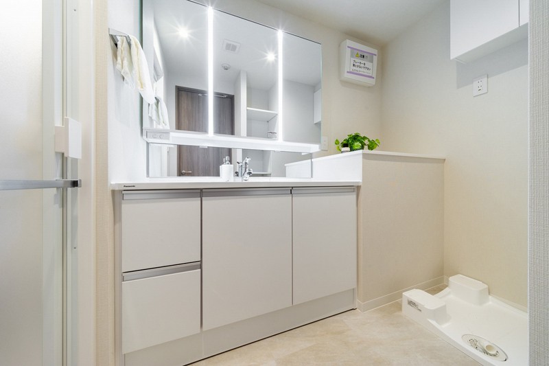 Panasonic製洗面化粧台を新しく設置した洗面室。白を基調とした清潔感のある空間です。洗濯機置場の上には便利な吊戸棚を備え付けています。