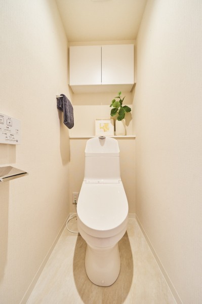 ウォシュレット一体型のトイレは、お掃除の手助けをしてくれる便利機能が搭載されています。上部にはインテリアを楽しめるカウンターや吊戸棚を造作しました。