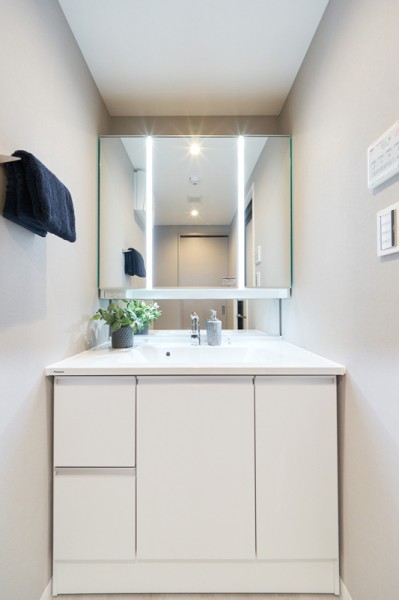 明るい三面鏡付きの洗面化粧台は洗面ボウル一体型、鏡裏と足元にも豊富な収納を備えています。