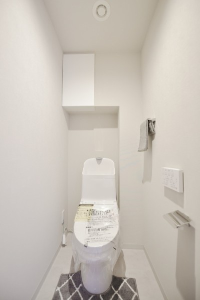 ウォシュレット一体型のトイレは、お掃除の手助けをしてくれる便利機能が搭載されています。上部の吊戸棚は小物の収納にも便利です。