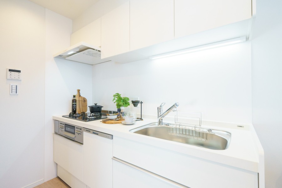 空間に溶け込む清潔感のあるキッチンは、三口コンロや食洗機が搭載された使い勝手良好なシステムキッチンです。壁付けなのでお手入れがしやすい点も魅力です。