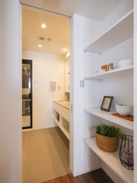 キッチンの奥には棚があります。カップボードに加えこちらにも食品などをたっぷりと収納できます。洗面室と繋がっており、家事動線に配慮した間取りになっています。
