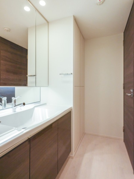 ゆとりのある洗面化粧台は大きな鏡が印象的なラグジュアリーな空間です。右手の収納にはリネンやランドリーグッズも収納可能です。