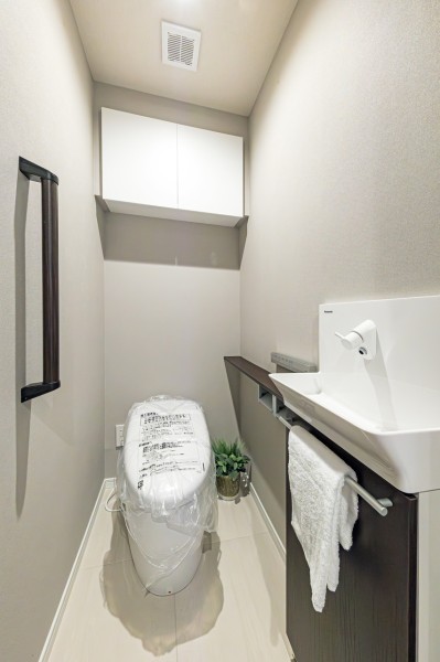 グレイッシュでモダンなレストルームにはスタイリッシュなタンクレストイレを備え付けました。上部吊戸棚とホテルライクな手洗いカウンター付きです。